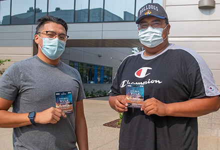 Two AHC fully vaccinated students holding $250 Visa gift cards.